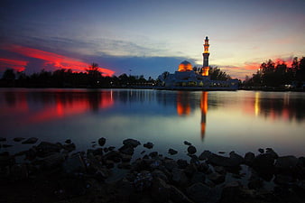 Illuminated Mosque Reflection at Sunset Over Calm Water