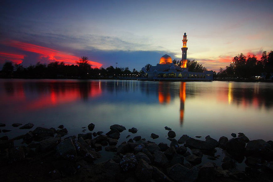 Illuminated Mosque Reflection at Sunset Over Calm Water