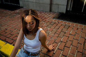 Young woman sitting on brick pavement in urban street setting
