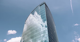 Modern Glass Skyscraper Reflecting Clouds Against Blue Sky