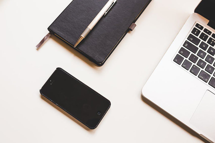 Minimalist workspace with laptop, smartphone, and notebook