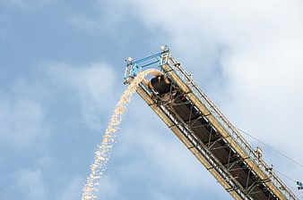 Industrial conveyor belt dumping salt against blue sky