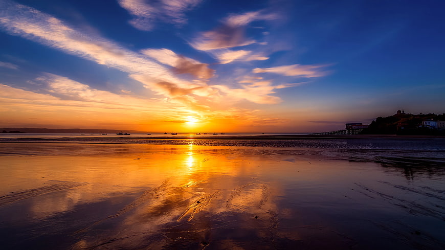 Golden Sunset Reflection on Wet Sandy Beach with Pier