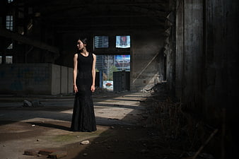 Woman in black dress standing in abandoned industrial ruins