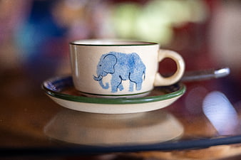 Ceramic teacup with blue elephant design on wooden table
