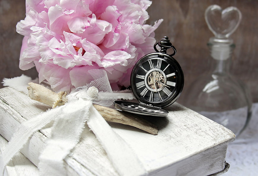 Vintage pocket watch and pink peony on old white book