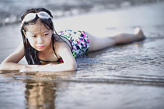 Young Girl in Swimsuit Lying on Wet Beach Sand