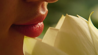 Close-up of woman's lips near white lotus flower