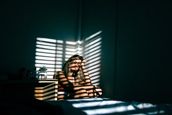 Woman sitting in bedroom with dramatic window shadows