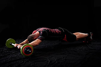 Athletic man performing barbell row exercise in dark gym