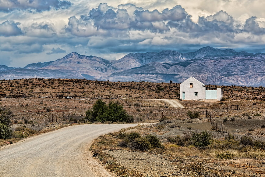 Lonely white farmhouse in the Karoo semi-desert landscape with mountains