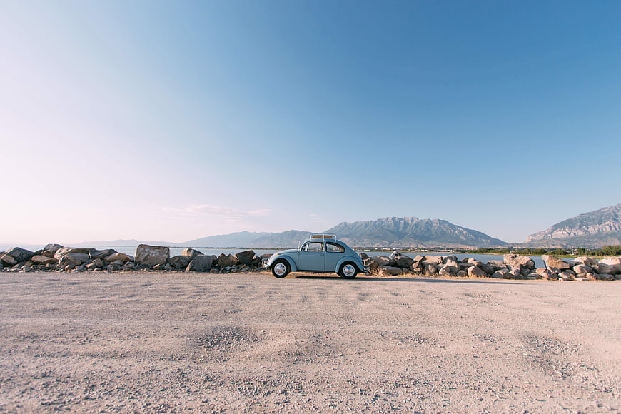 Vintage Blue Volkswagen Beetle Parked by Rocky Shoreline