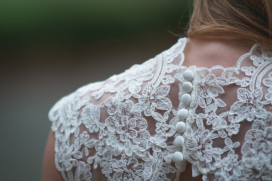 Close-up of white lace wedding dress back with pearl buttons