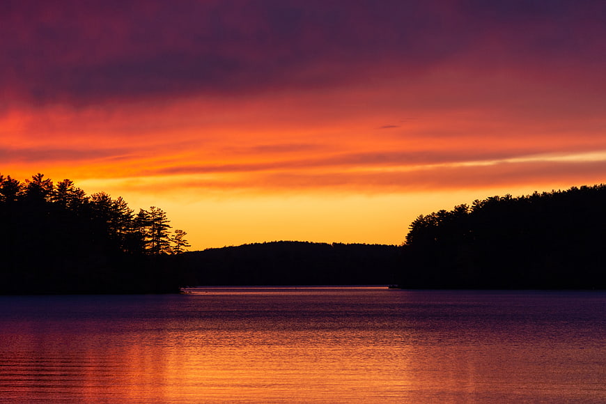 Vibrant Sunset Over Lake with Silhouetted Forest