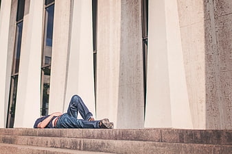 Man lying on concrete steps in front of modern building