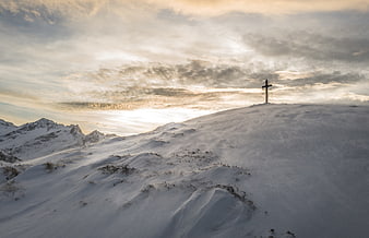 Snowy Mountain Peak with Cross at Sunset