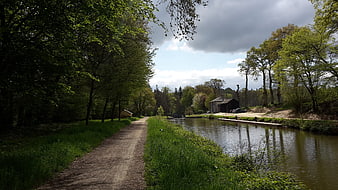 Peaceful Canal Path Lined with Green Trees and Barn