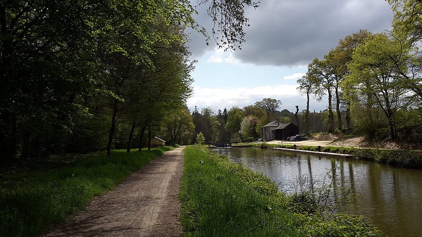 Peaceful Canal Path Lined with Green Trees and Barn