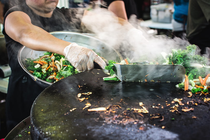 Chef grilling fresh vegetables on a large flat top grill