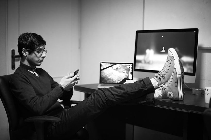 Man with feet on desk using smartphone in office
