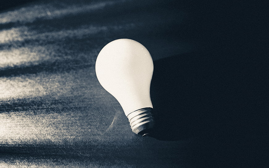 Frosted light bulb on textured dark background with shadows