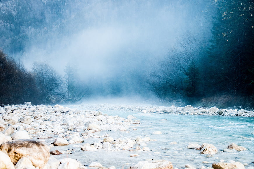 Misty river flowing through rocky forest landscape in winter