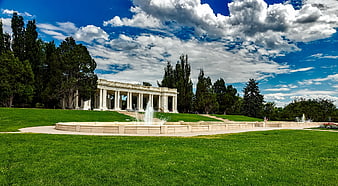 Classical colonnade building with fountain and green lawn