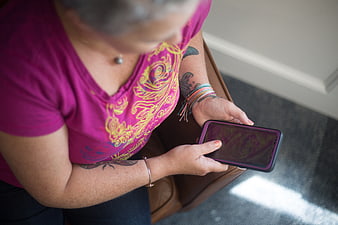 Senior woman with tattoos using smartphone indoors