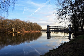 Serene River Landscape with Historic Lock and Bare Trees