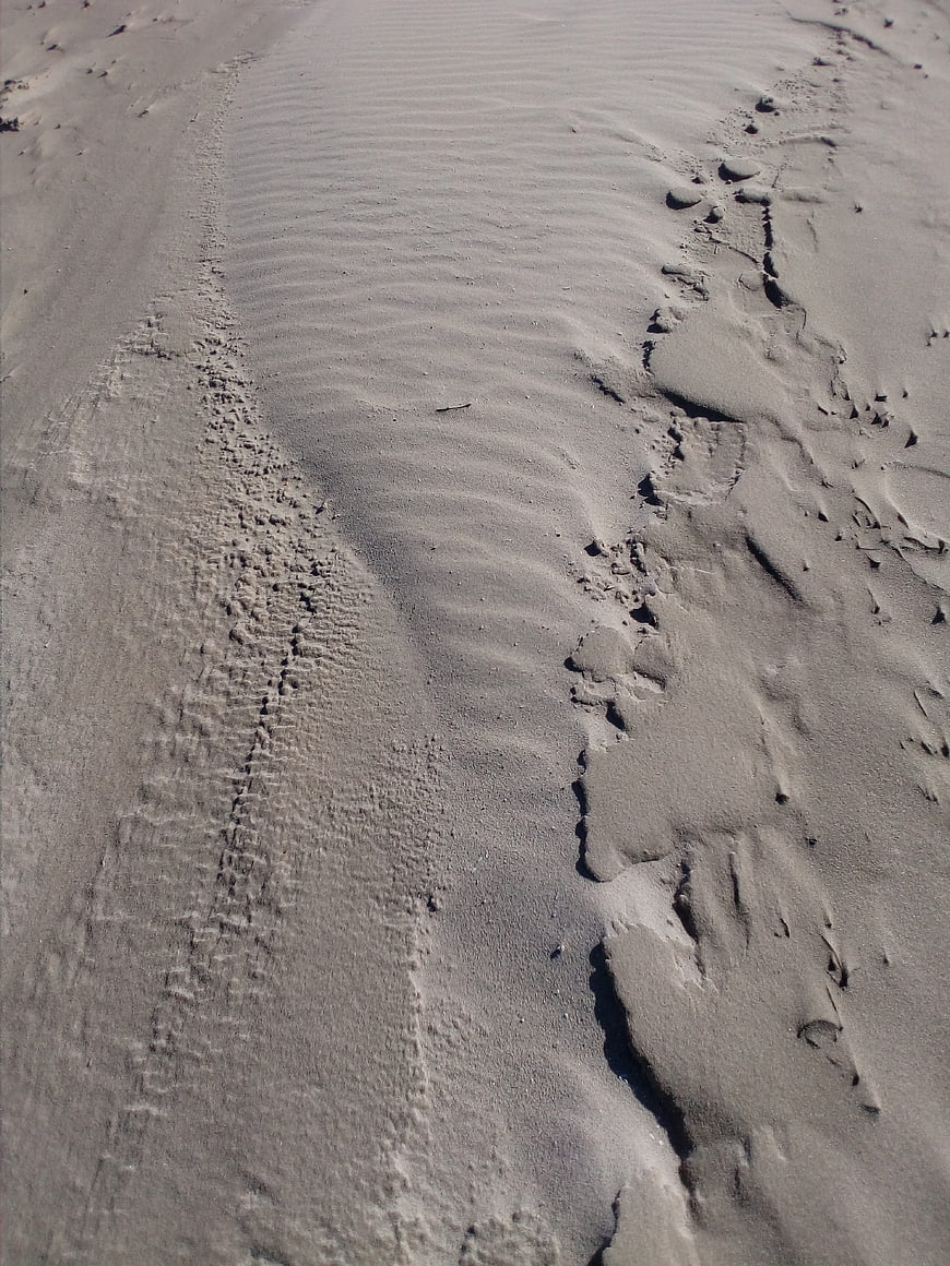 Close-up of textured sand ripples and footprints on a beach