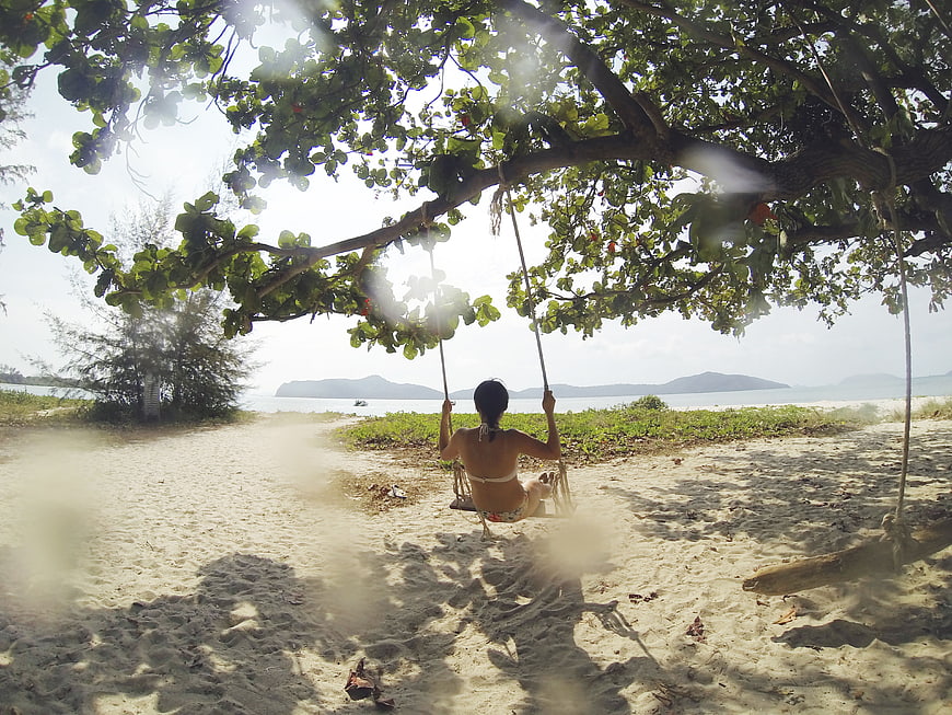 Woman relaxing on a beach swing under a tree