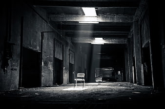 Lone Chair in Abandoned Industrial Hall with Light Beams