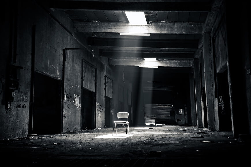 Lone Chair in Abandoned Industrial Hall with Light Beams