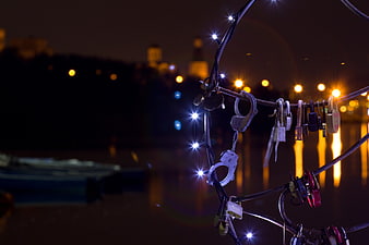 Love locks and handcuffs on railing at night with city lights