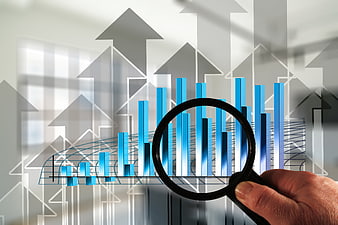 Hand holding magnifying glass over business growth chart