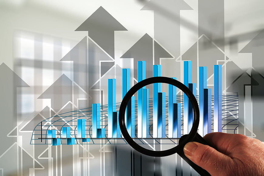 Hand holding magnifying glass over business growth chart