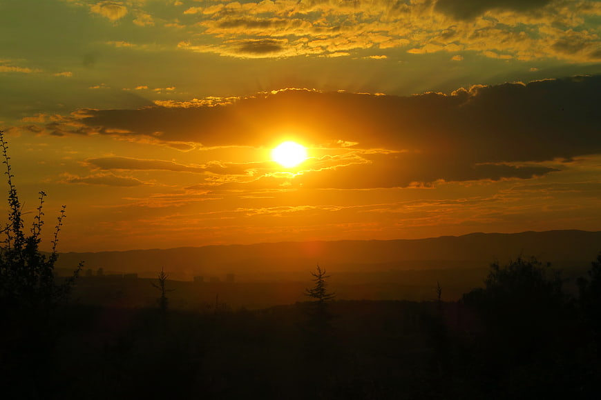 Golden Sunset Over Silhouetted Hills and Forest