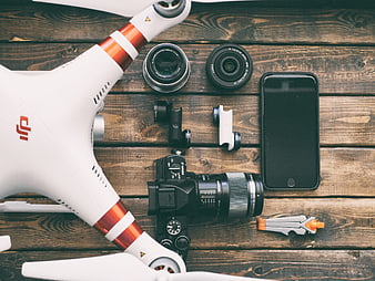 Flat lay of drone, camera, lenses, and smartphone on wooden table