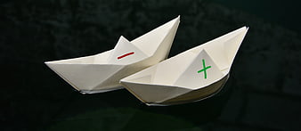 Two paper boats with plus and minus signs on dark water