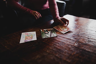 Woman's hand placing watercolor art on rustic wooden table