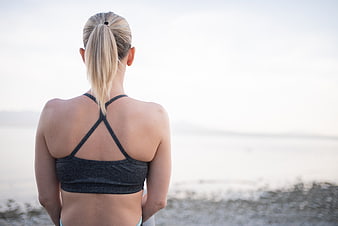 Woman in sports bra meditating by the ocean