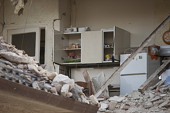 Damaged kitchen interior with rubble and debris after earthquake