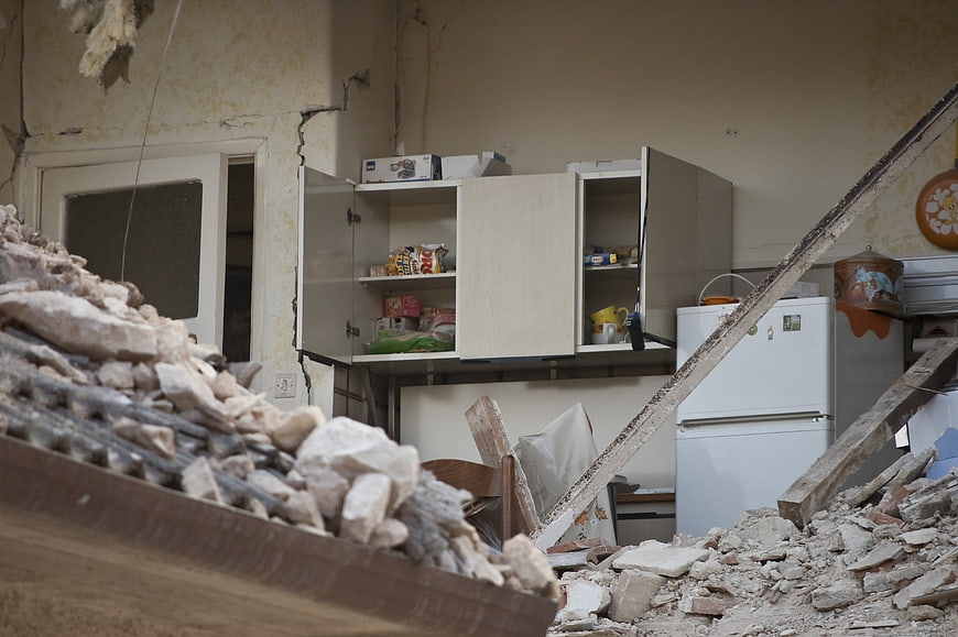 Damaged kitchen interior with rubble and debris after earthquake
