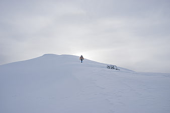 Lone Hiker Walking Up Snowy Mountain Ridge