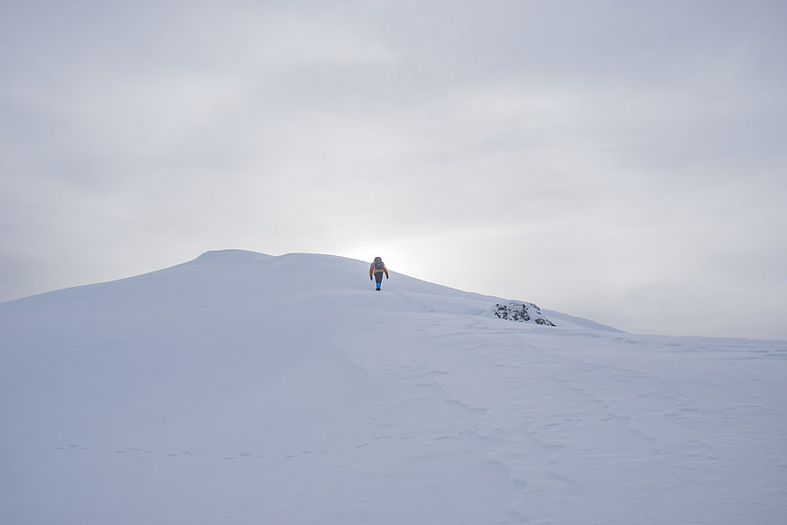 Lone Hiker Walking Up Snowy Mountain Ridge
