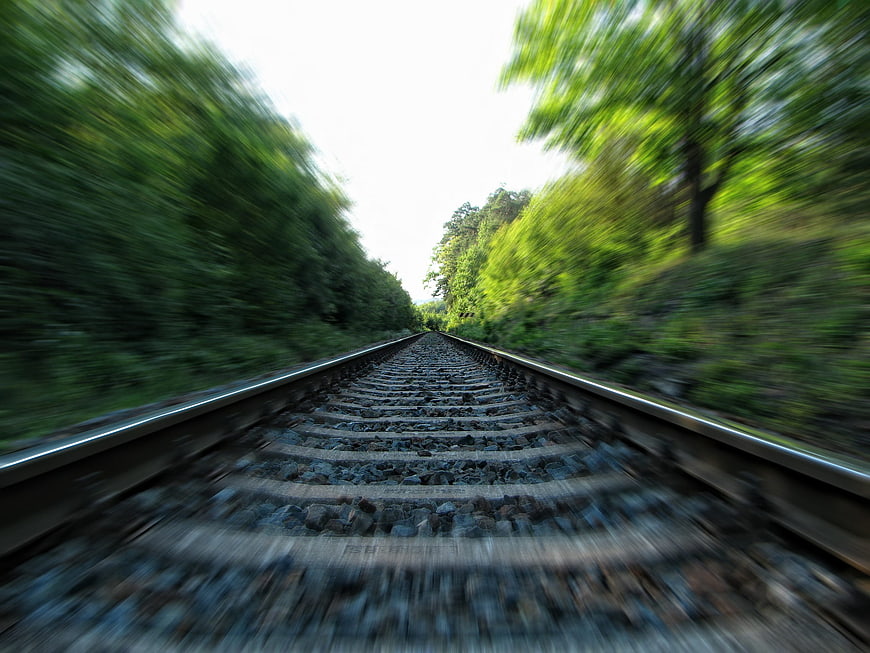 Motion blur view of railway tracks through green forest