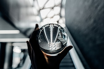 Hand holding crystal sphere reflecting modern architecture