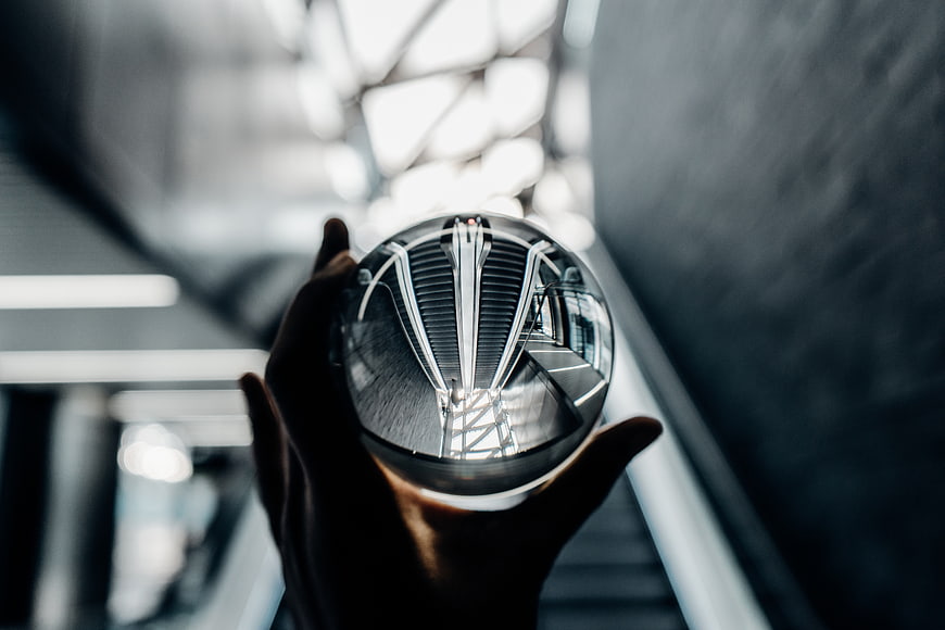Hand holding crystal sphere reflecting modern architecture