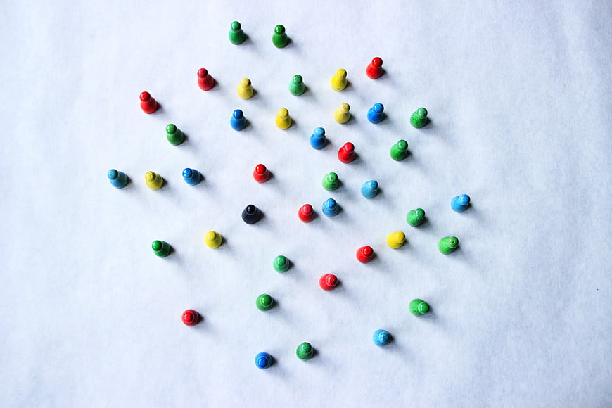 Colorful wooden game pieces on white paper background