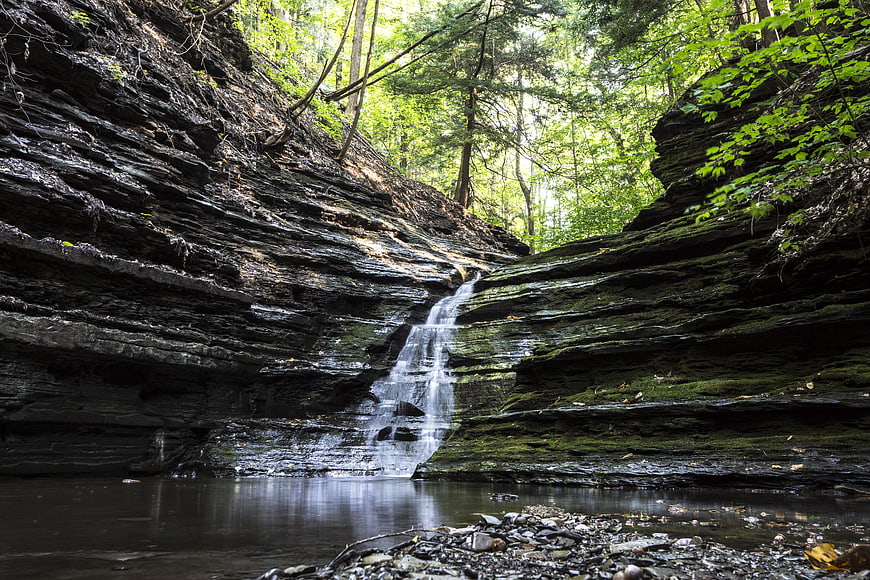 Small waterfall cascading down layered rocks in a lush forest